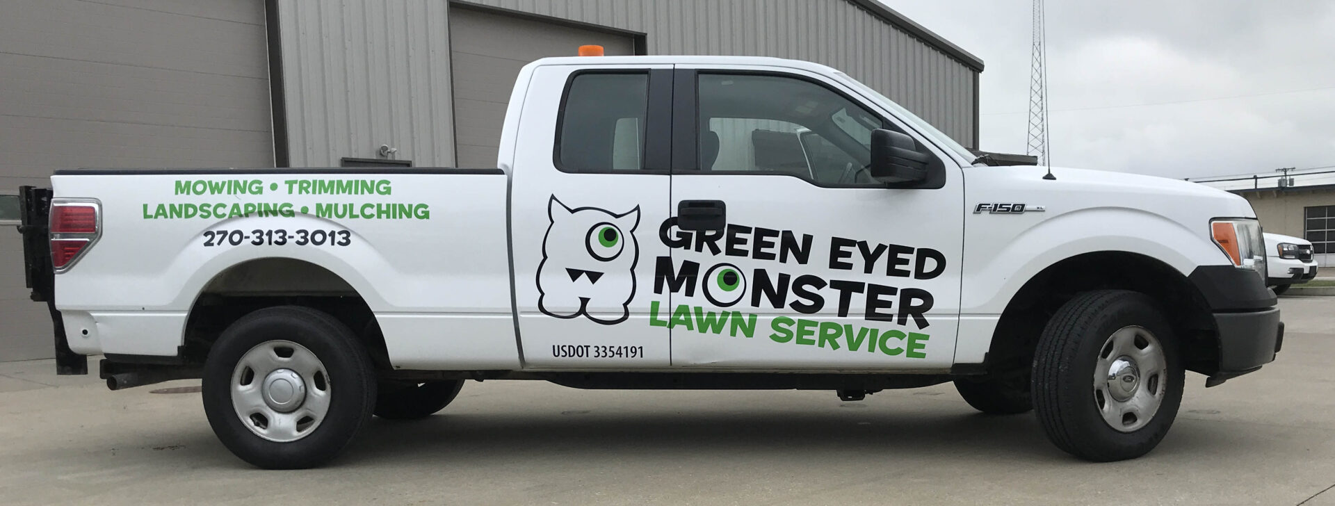 A white truck with green eyes and monster lettering on the side.