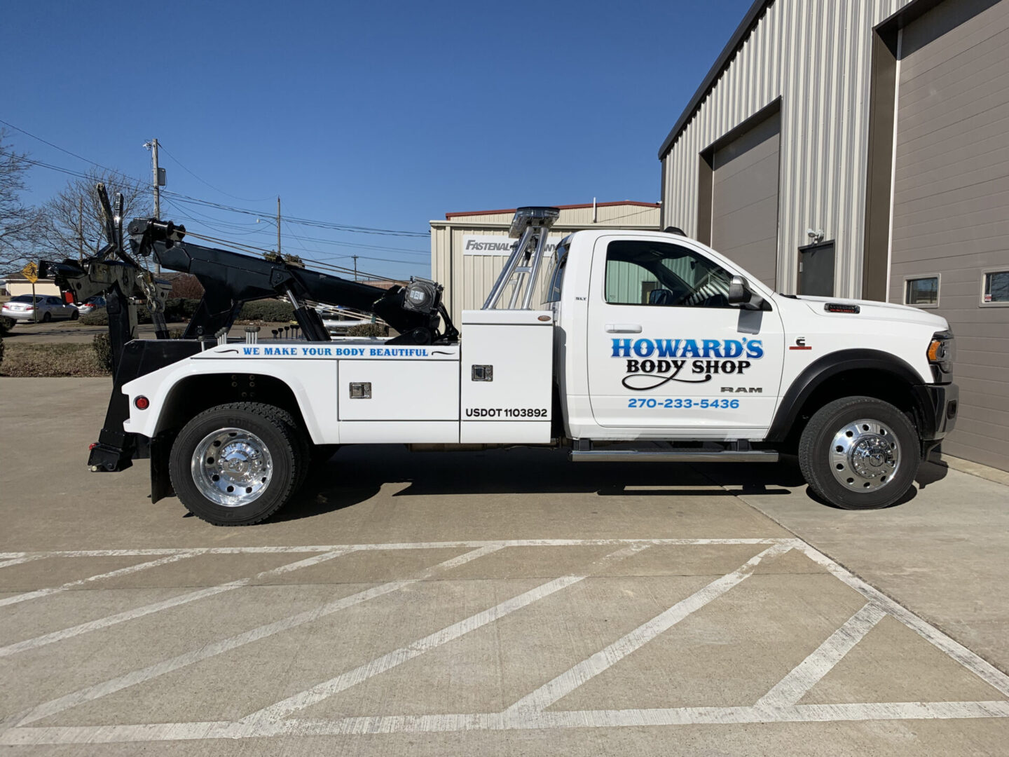 A tow truck parked in the parking lot of a building.