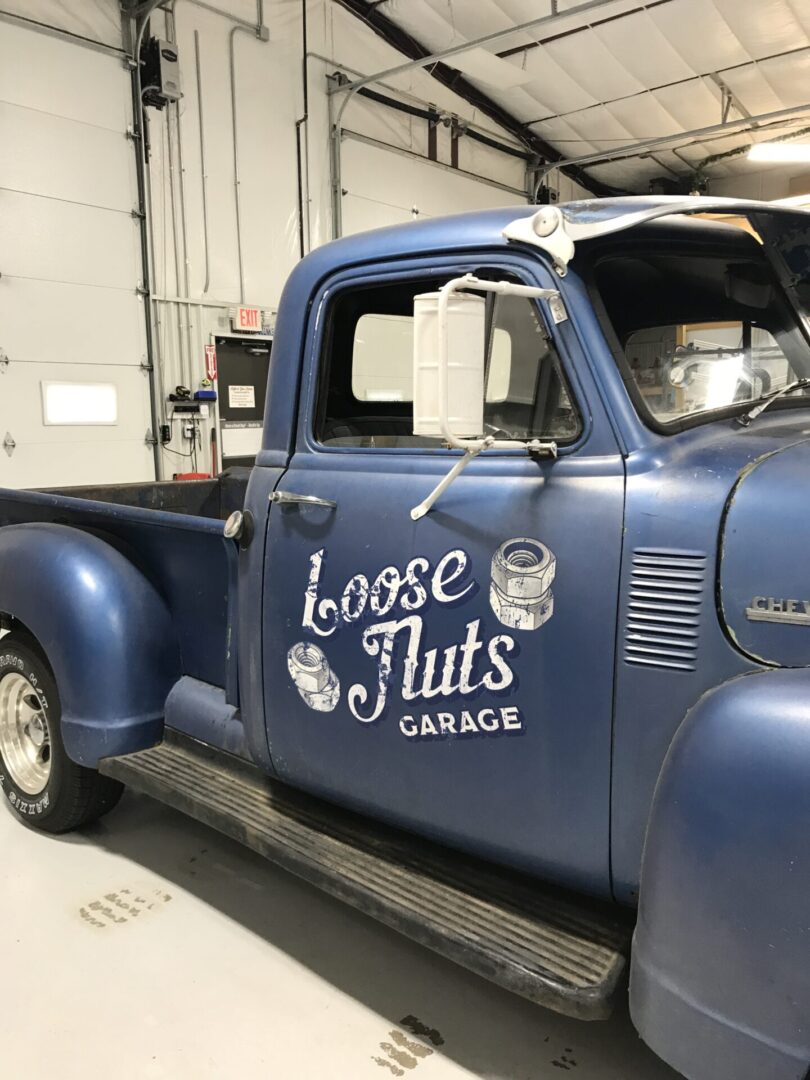 A blue truck with the words loose nuts garage on it.