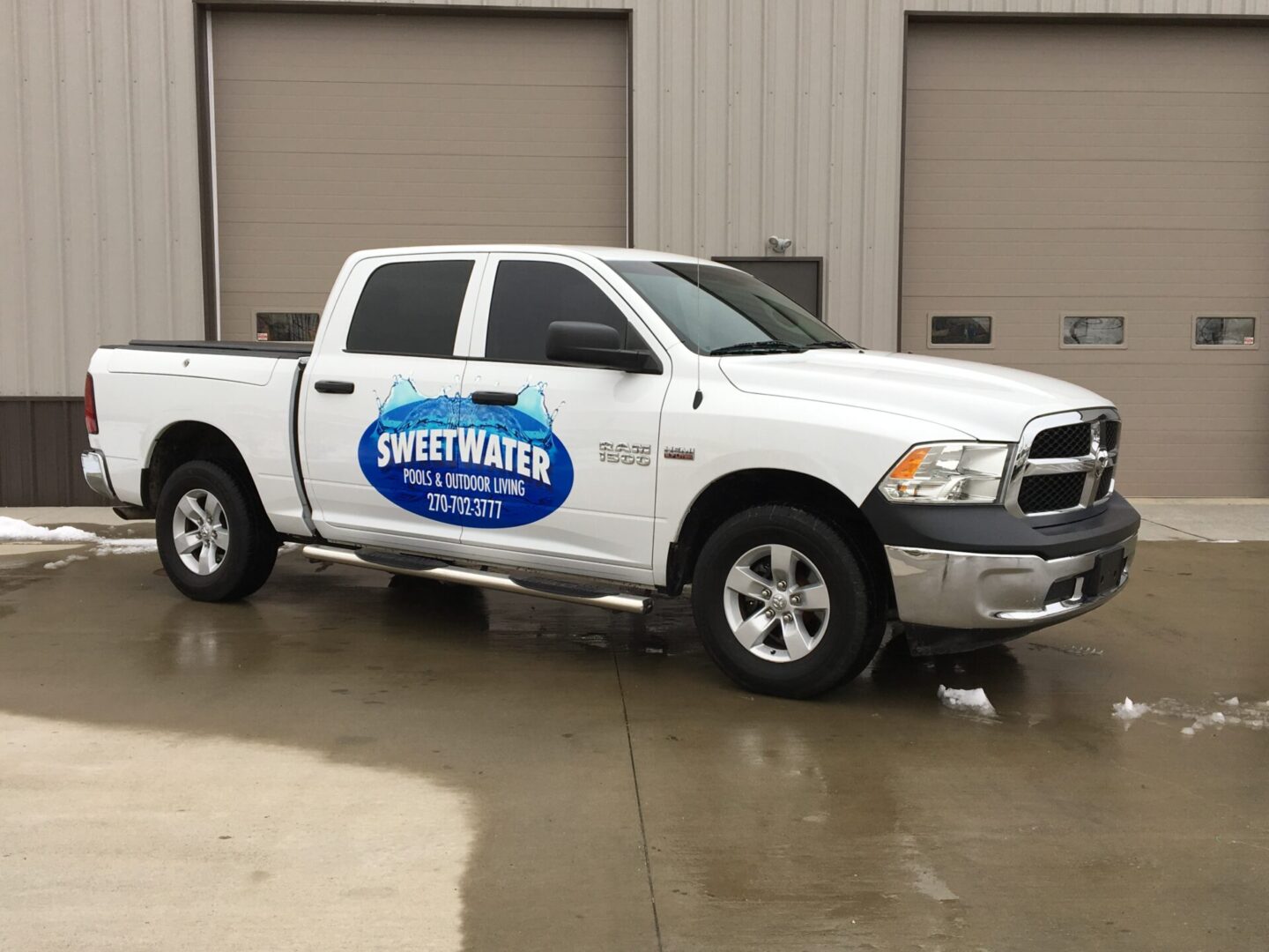 A white truck parked in front of two garage doors.