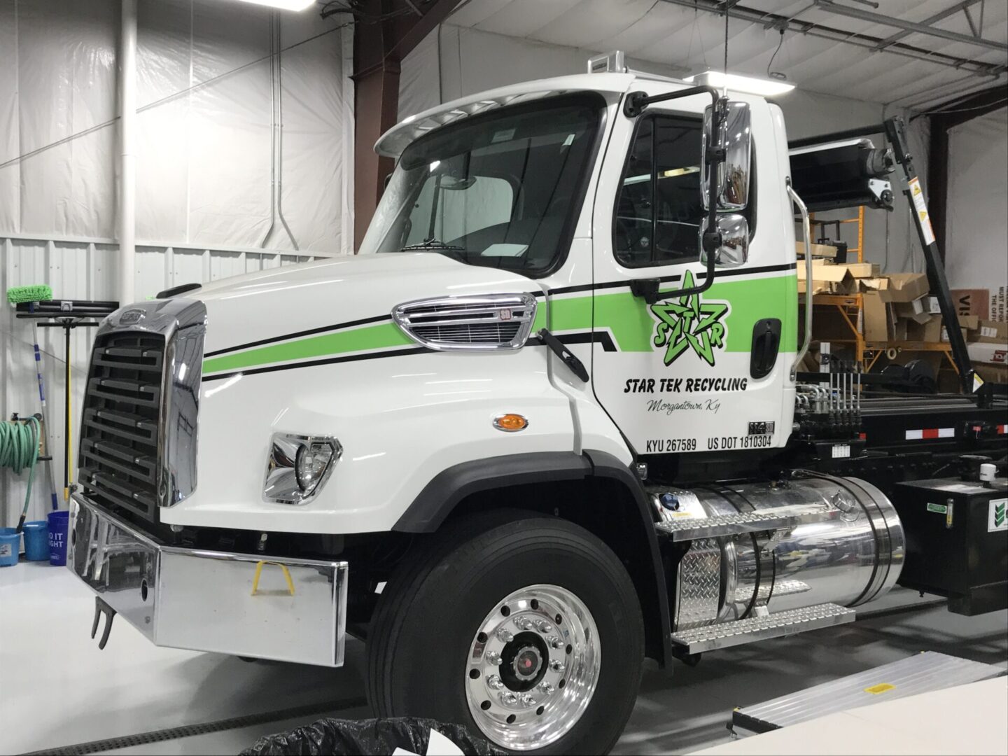 A white and green truck is parked in the garage.