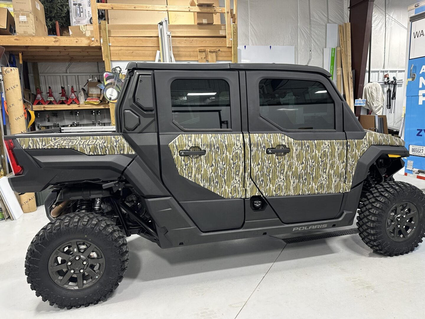 A camouflage truck is parked in the garage.