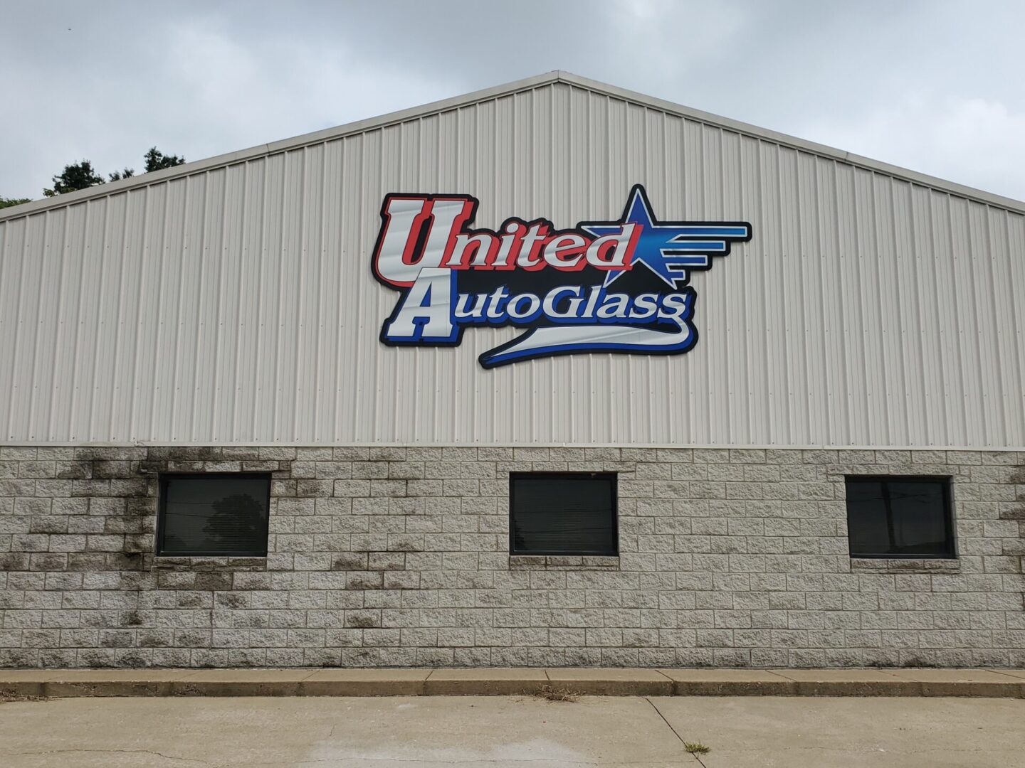 A large white building with the words united autoglass on it.