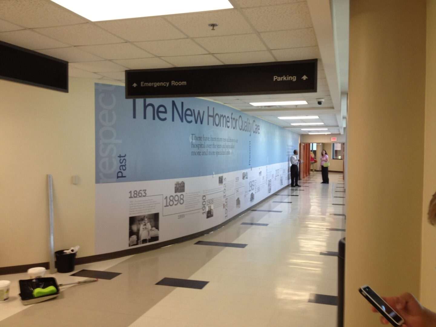 A hallway with people walking around and a large sign on the wall.