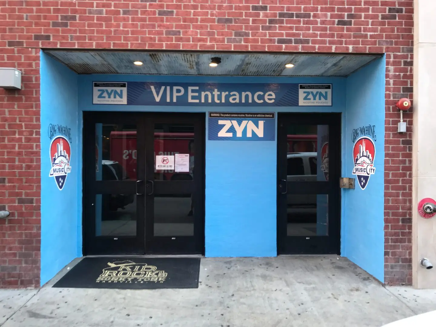 A blue building with two doors and a black door mat.