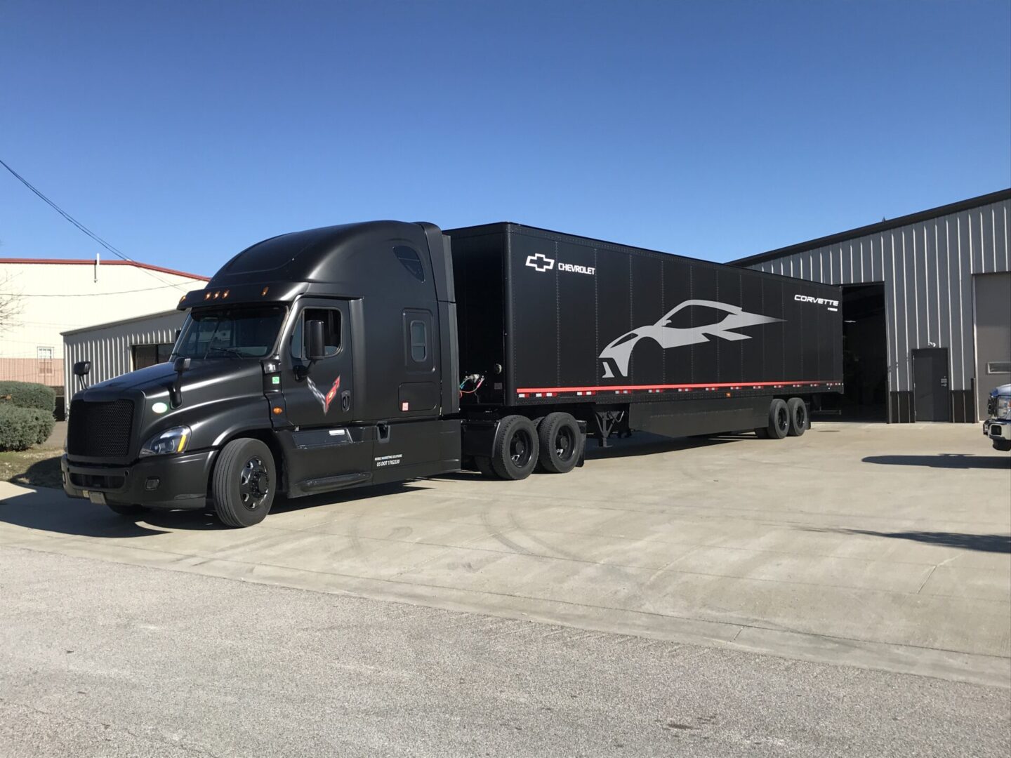 A black semi truck with a trailer parked in front of it.