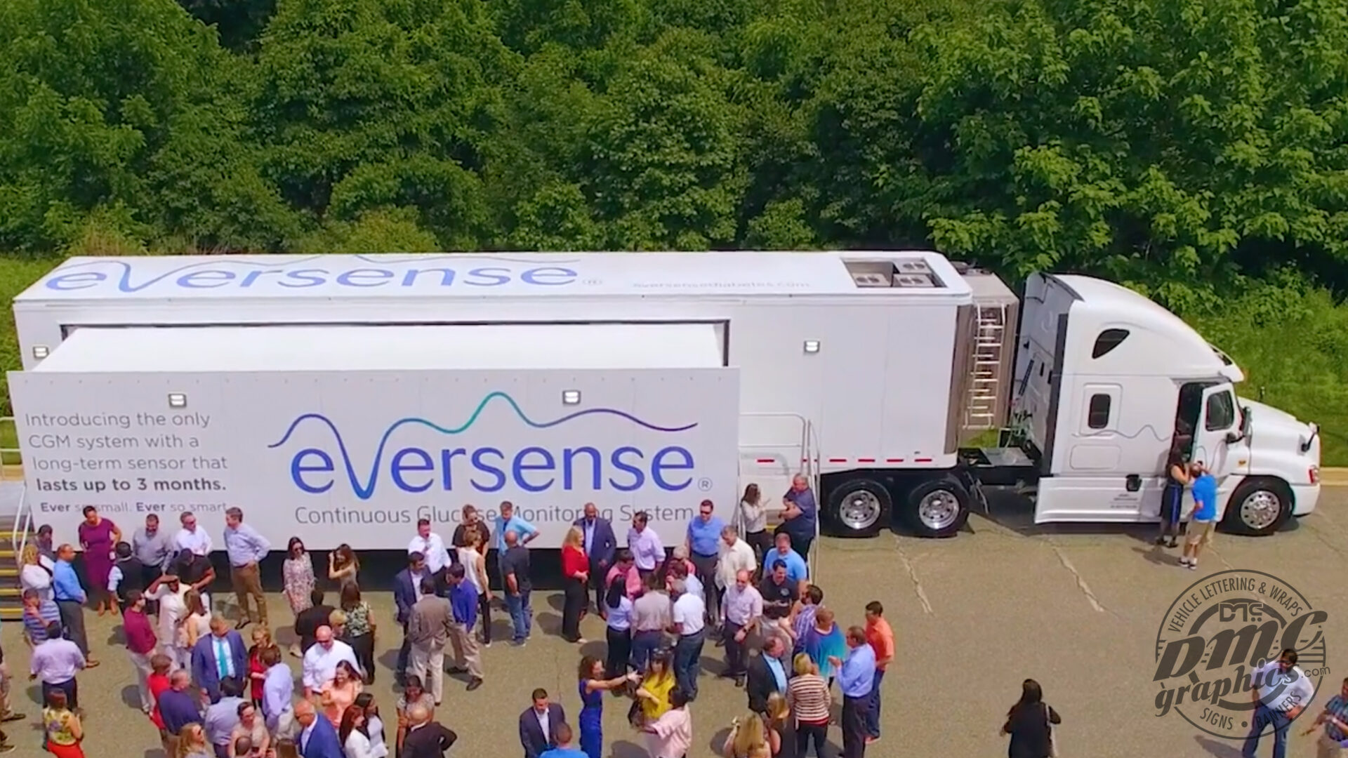 A large group of people standing around an eversense truck.