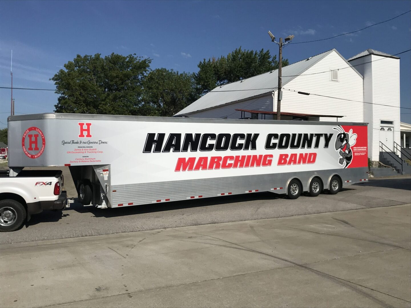 A large white trailer with the words hancock county marching band on it.