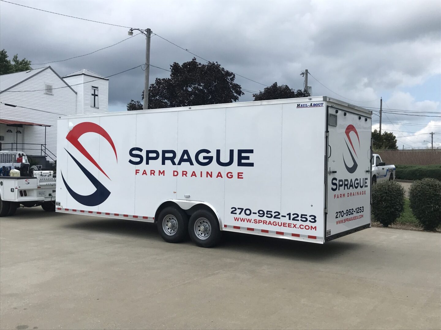 A white trailer with the sprague farm drainage logo on it.