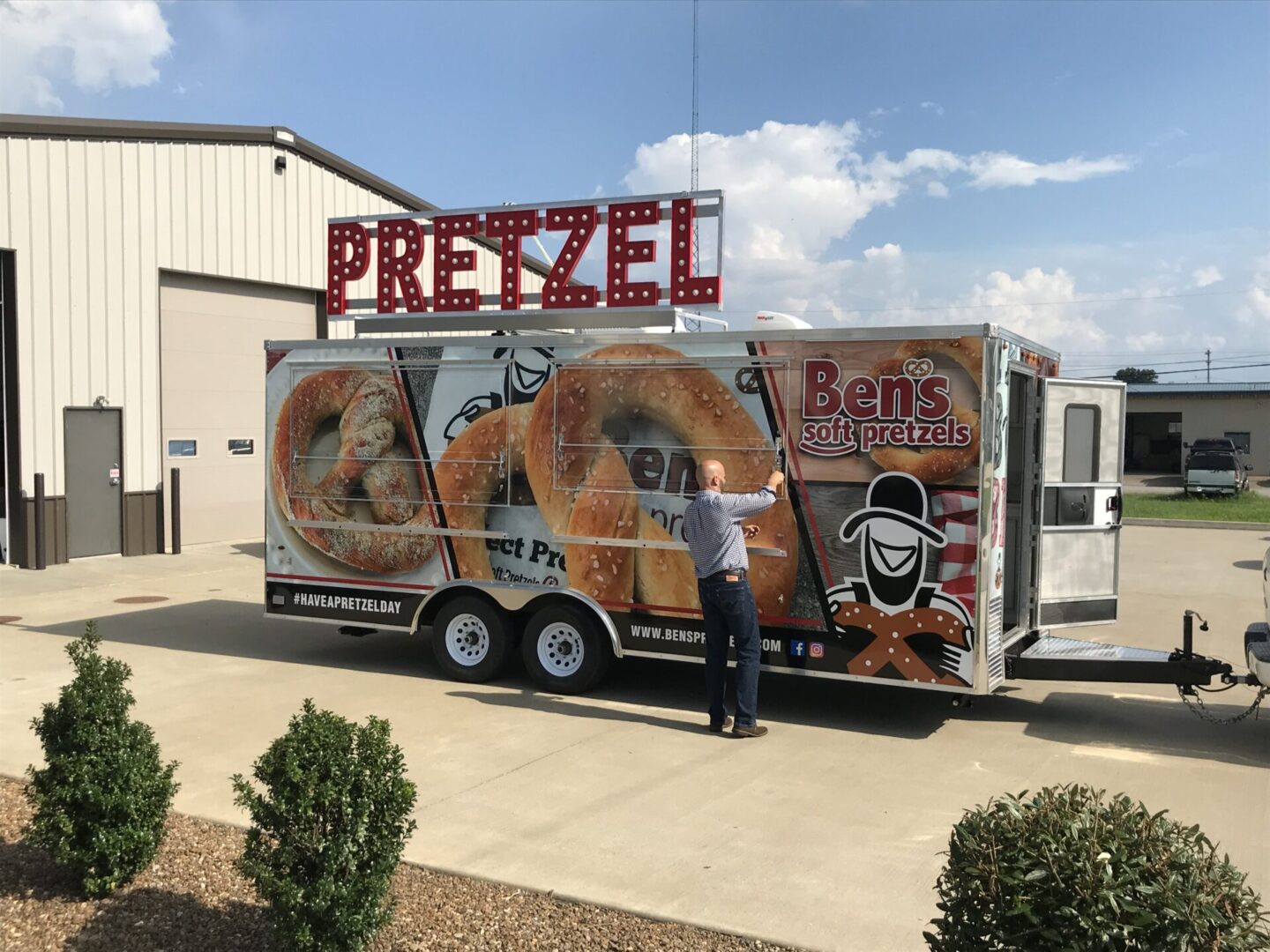 A man standing in front of a trailer with pretzels on it.