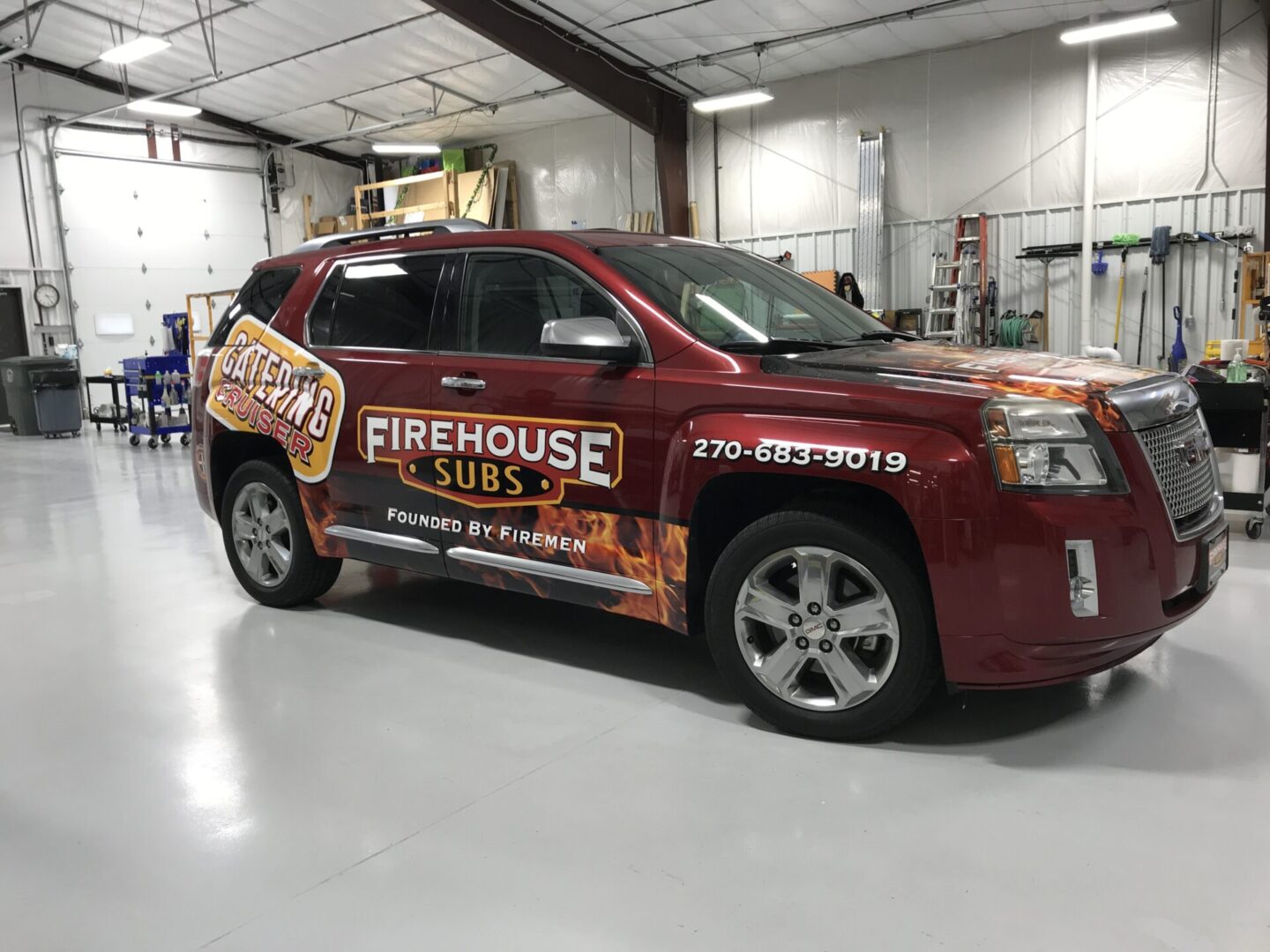 A red suv parked in a warehouse with advertising on the side.