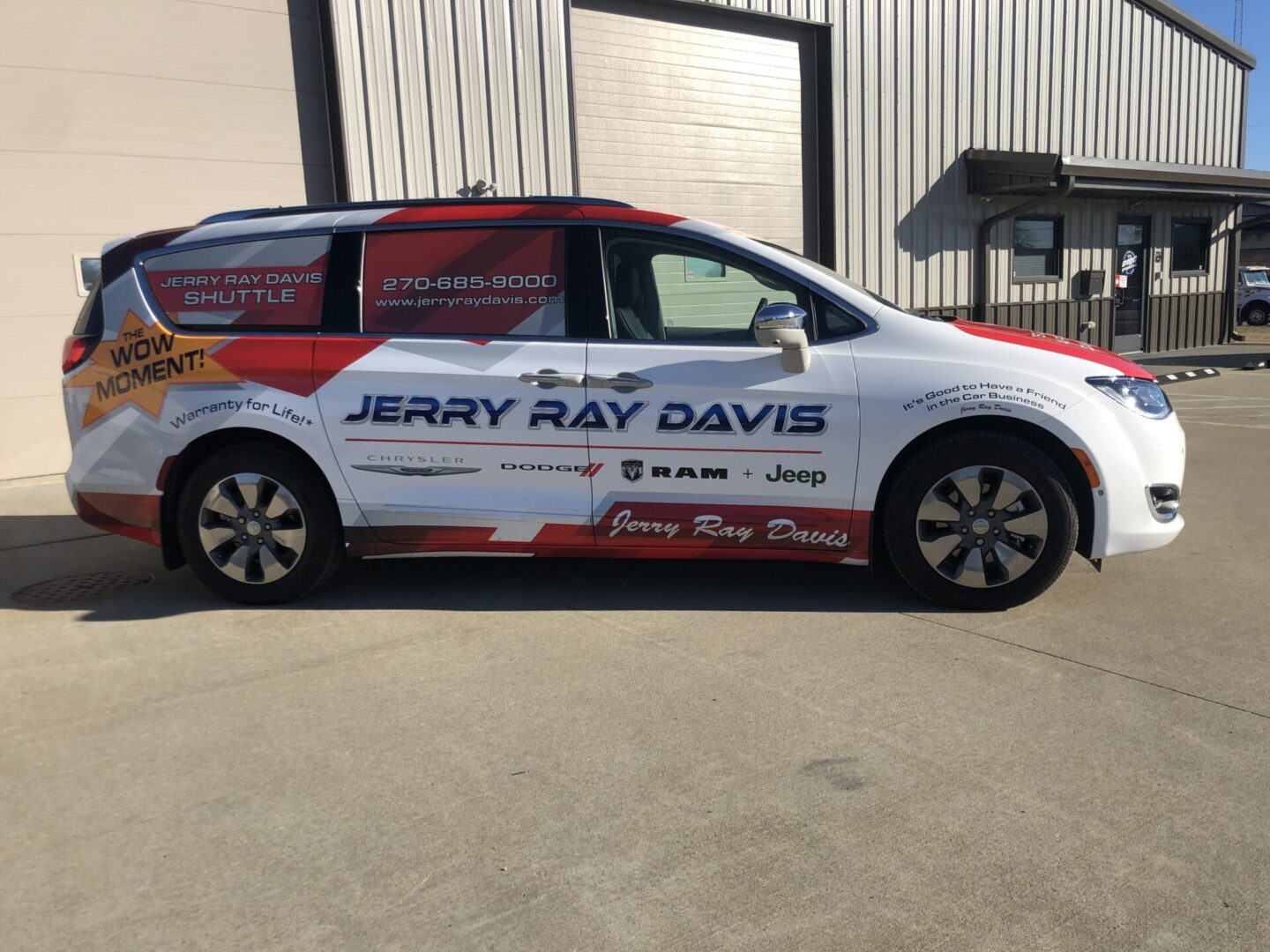 A white van with red and black lettering parked in front of a building.