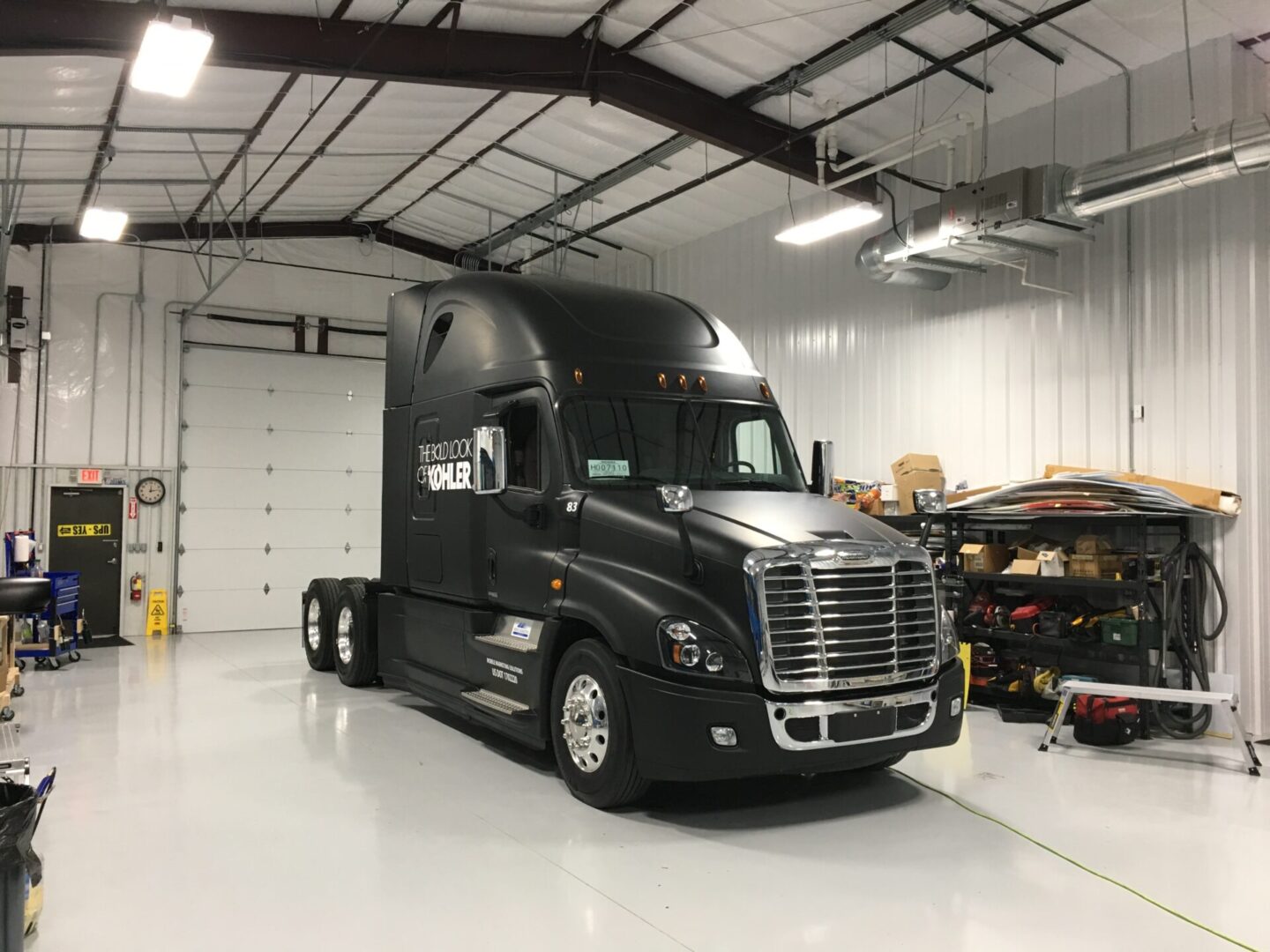 A black semi truck parked in a garage.