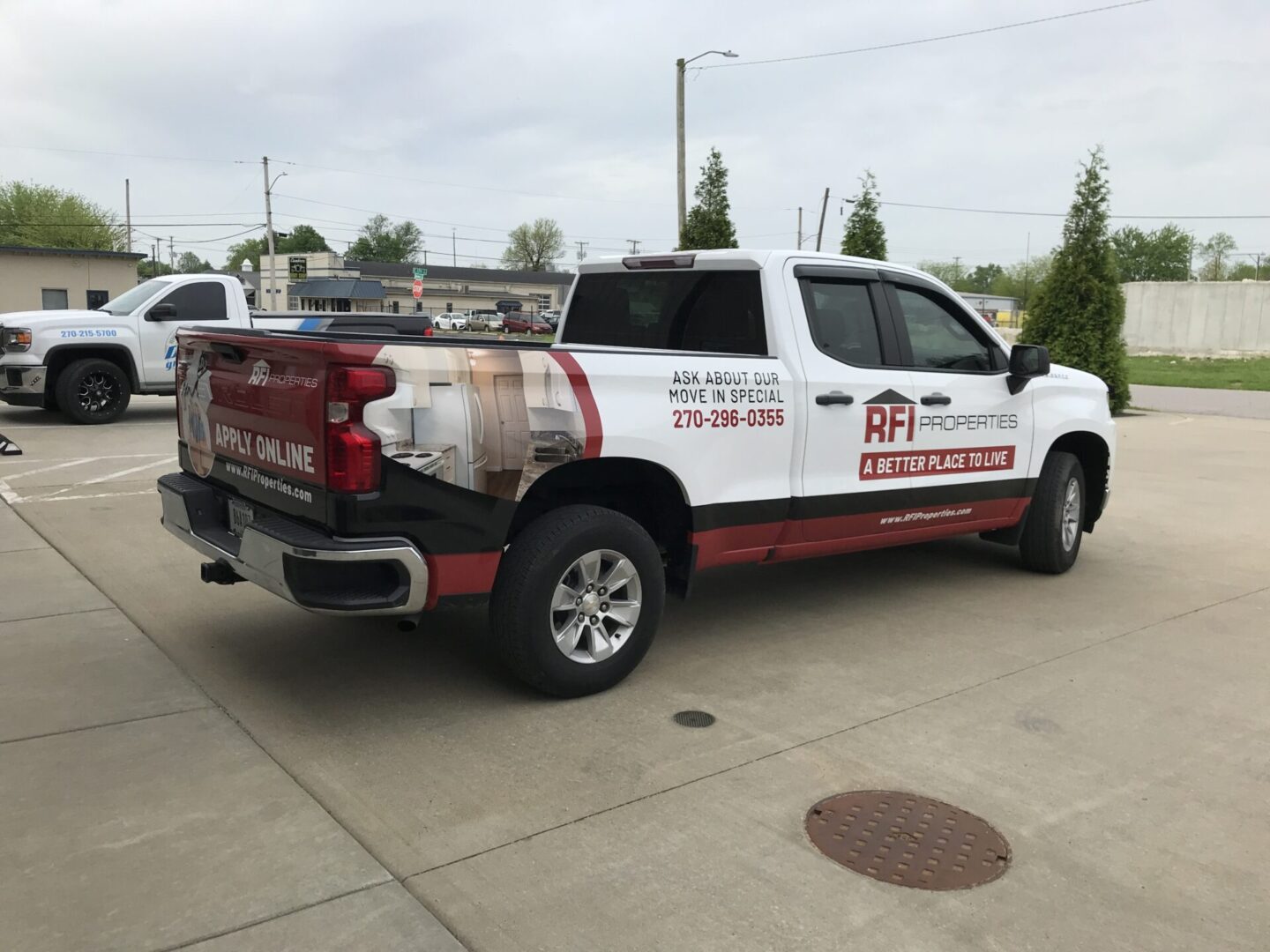 A white truck with red and black lettering parked on the side of a road.