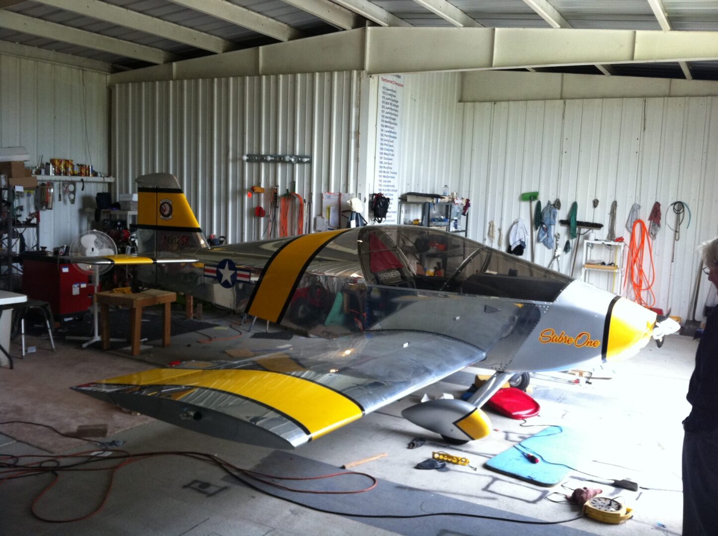 A small airplane in a garage with many tools.