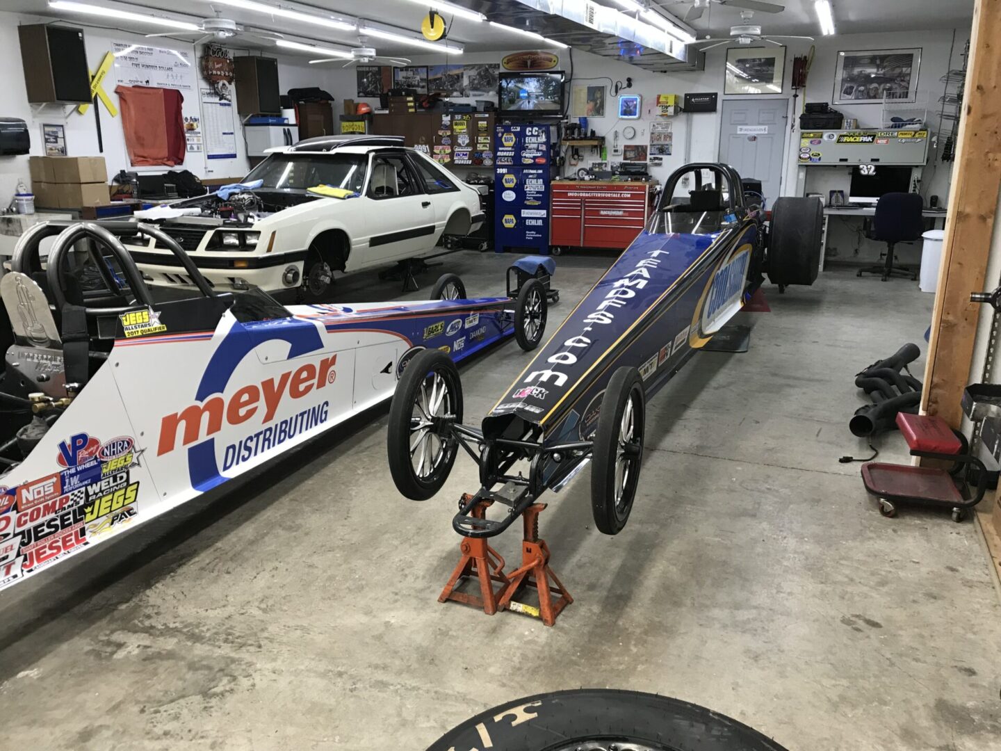 A garage with several cars and a racing car.